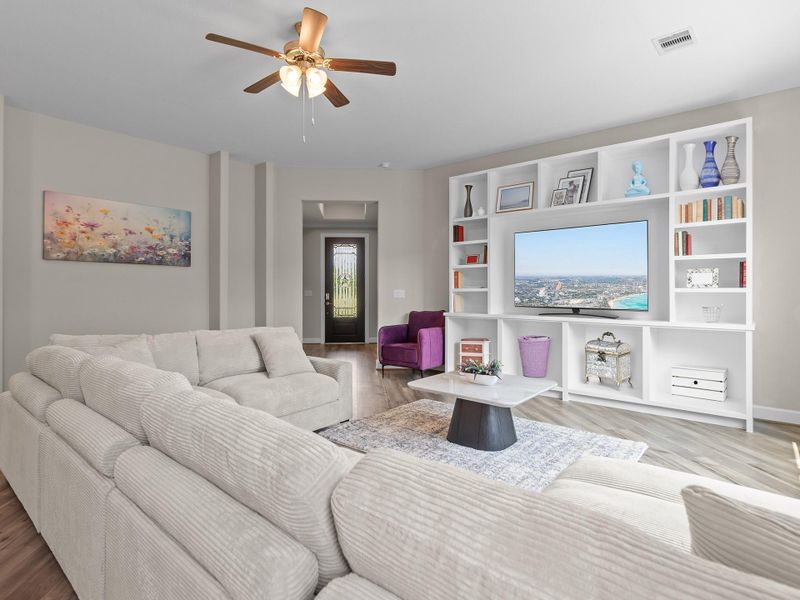 The living room space in the Promenade III  features an expansive, light-filled area with large windows and a versatile layout perfect for both entertaining and everyday living. Image depicts home as-is with some elements virtually staged.