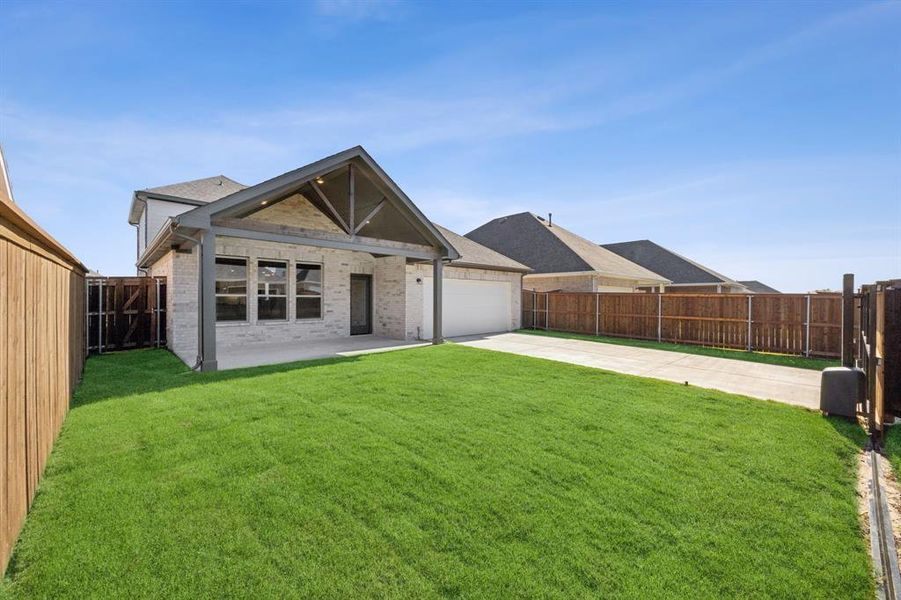 Rear view of house featuring a lawn, a garage, and a patio