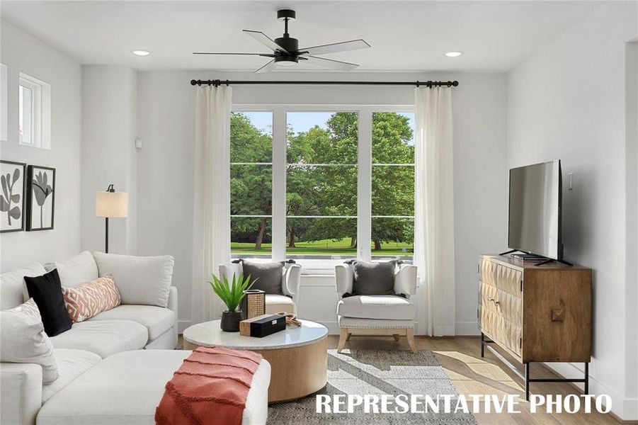 Living room with ceiling fan and light hardwood / wood-style floors