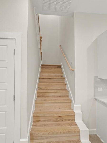 Natural wood-finish staircase with crisp white risers and baseboards