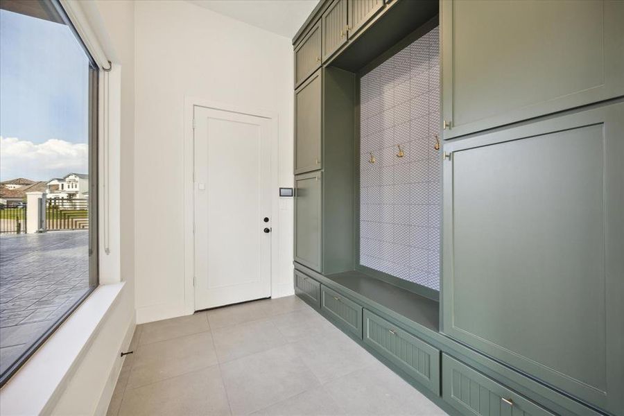 As you enter the home through the garage, you're greeted by a thoughtfully designed dry mudroom. This practical space is perfect for storing coats, shoes, and outdoor gear, keeping the rest of the home clean and organized. Featuring built-in cubbies, hooks, and benches, the mudroom offers ample storage and seating to make transitioning from outdoors to indoors seamless.