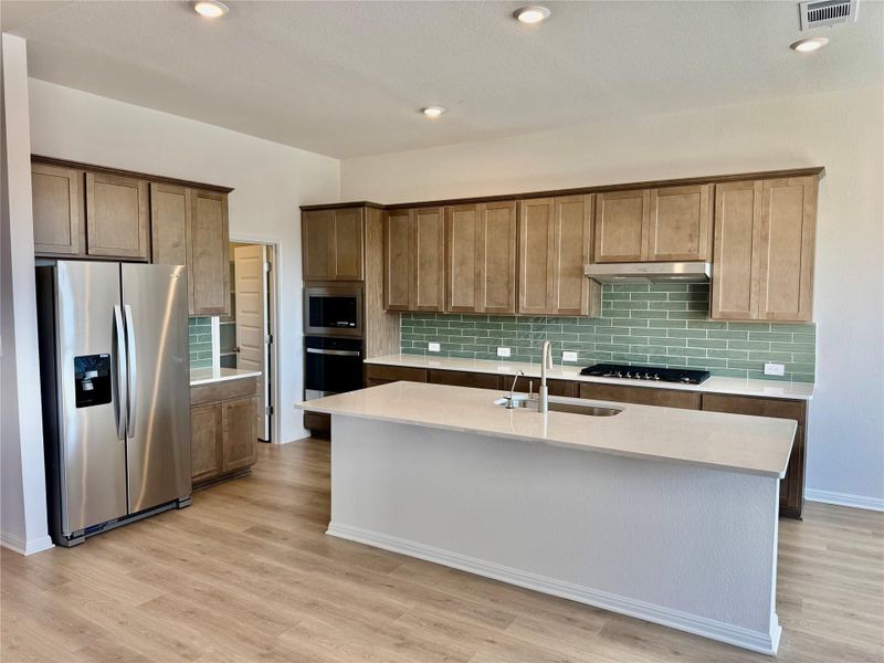 Kitchen featuring appliances with stainless steel finishes, tasteful backsplash, recessed lighting, light stone counters, and light wood-type flooring Kitchen featuring appliances with stainless steel finishes, tasteful backsplash, recessed lighting, light stone counters, and light wood-type flooring