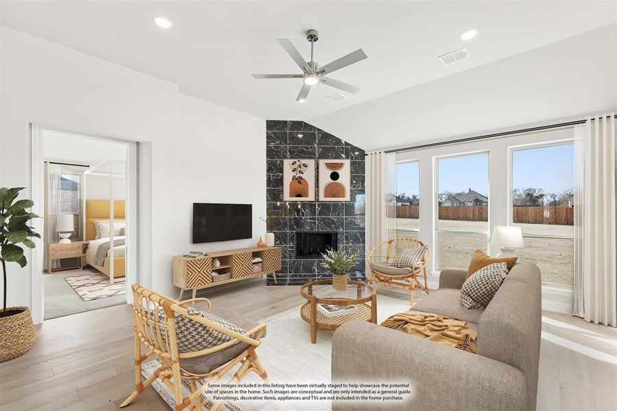 Living room with dark tile fireplace, ceiling fan, large windows, and wood floors Living room with dark tile fireplace, ceiling fan, large windows, and wood floors