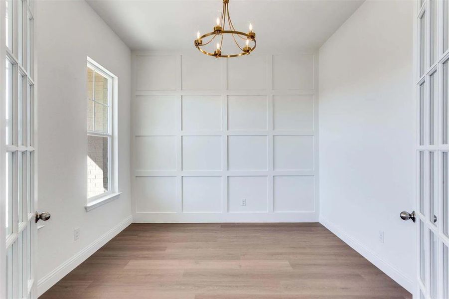 Unfurnished dining area with light wood finished floors, a decorative wall, and a chandelier Unfurnished dining area with light wood finished floors, a decorative wall, and a chandelier