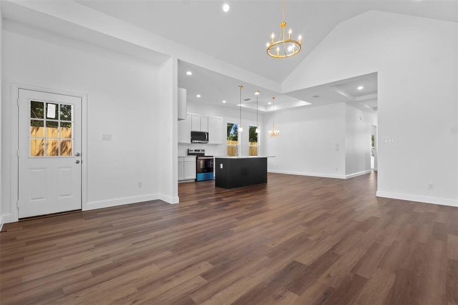 Unfurnished living room with a chandelier, recessed lighting, dark wood-style flooring, and high vaulted ceiling