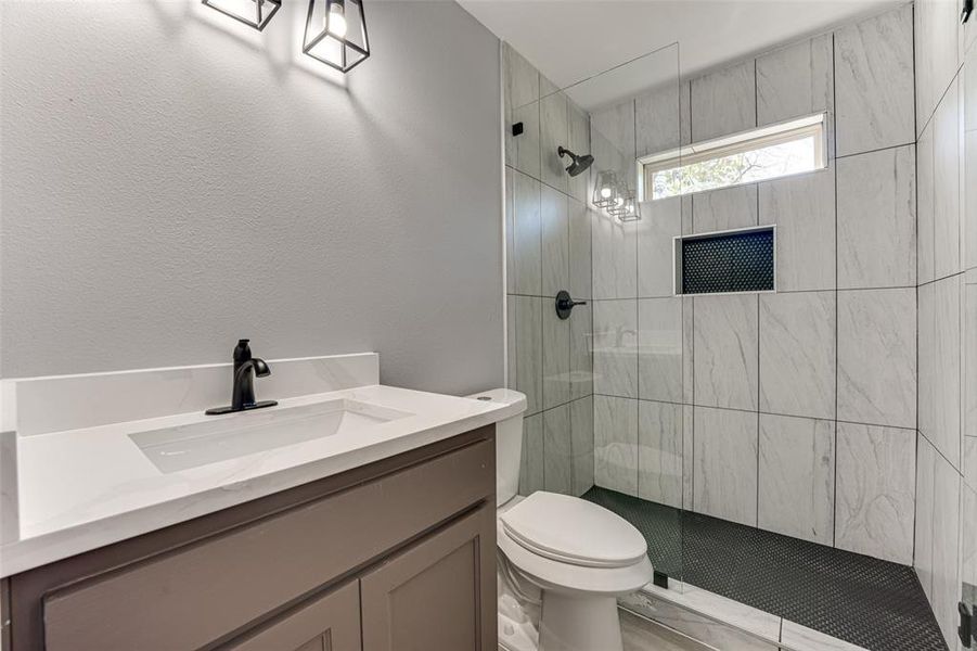 Bathroom with vanity, toilet, and a tile shower