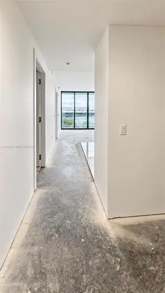 Interior hallway featuring floor-to-ceiling black-framed glass panels, recessed ceiling lighting, and polished stone tile flooring Interior hallway featuring floor-to-ceiling black-framed glass panels, recessed ceiling lighting, and polished stone tile flooring