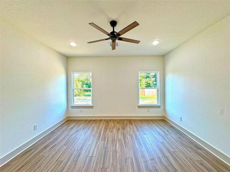 Spare room featuring a textured wall, a textured ceiling, wood finished floors, and ceiling fan Spare room featuring a textured wall, a textured ceiling, wood finished floors, and ceiling fan
