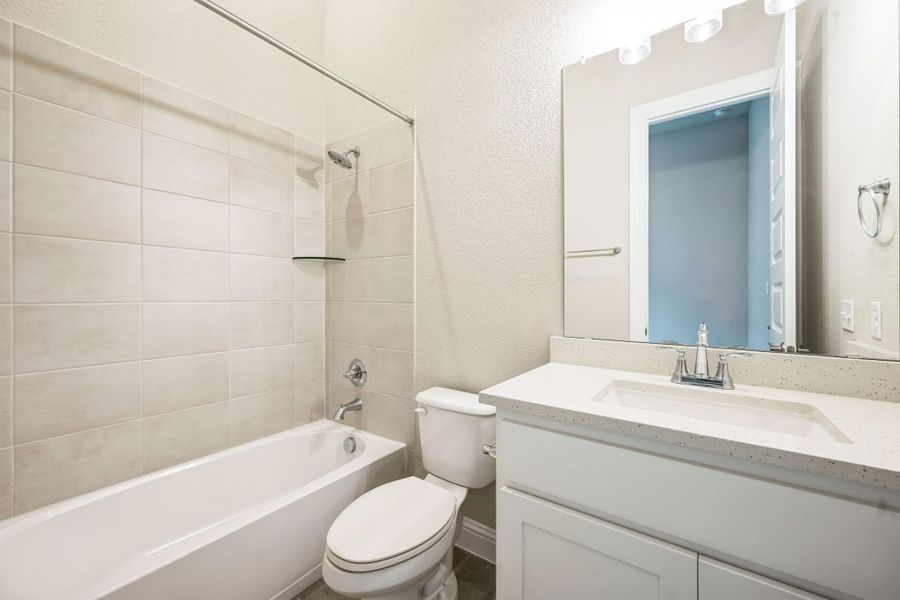 Full bath with a textured wall, vanity, shower / tub combination, and toilet Full bath with a textured wall, vanity, shower / tub combination, and toilet