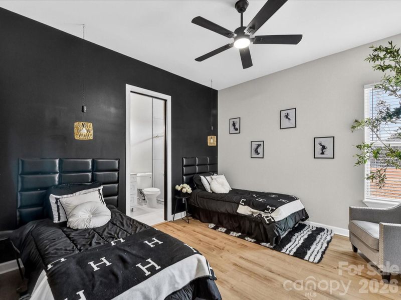 Stylish bedroom with dual beds, bold accent wall, modern lighting, and a private ensuite for added convenience.