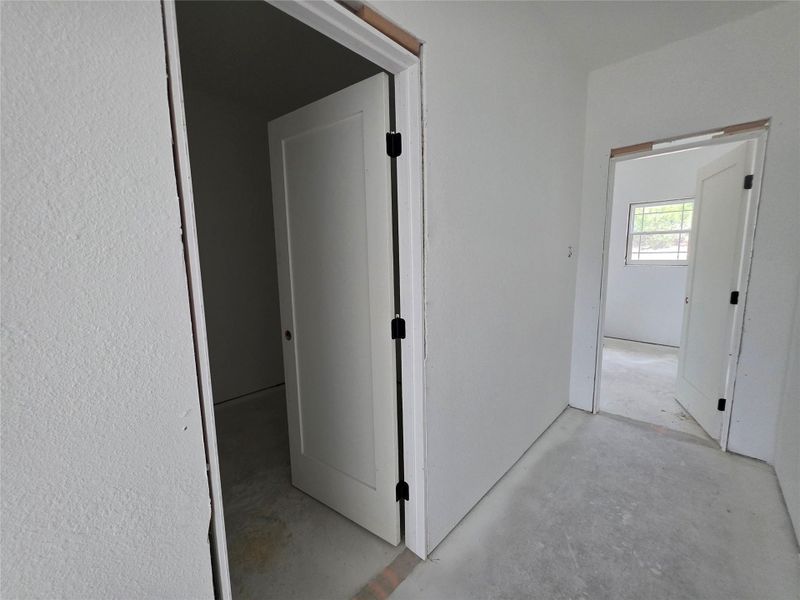 Interior corridor featuring multiple doorways with white panel doors and black hardware