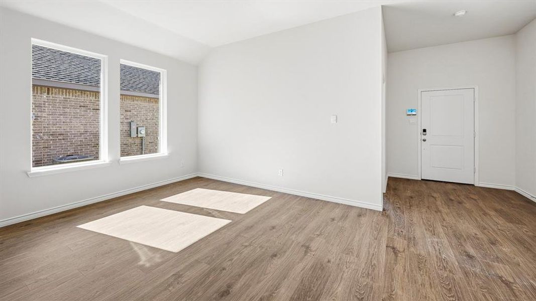 Spare room with wood finished floors and lofted ceiling