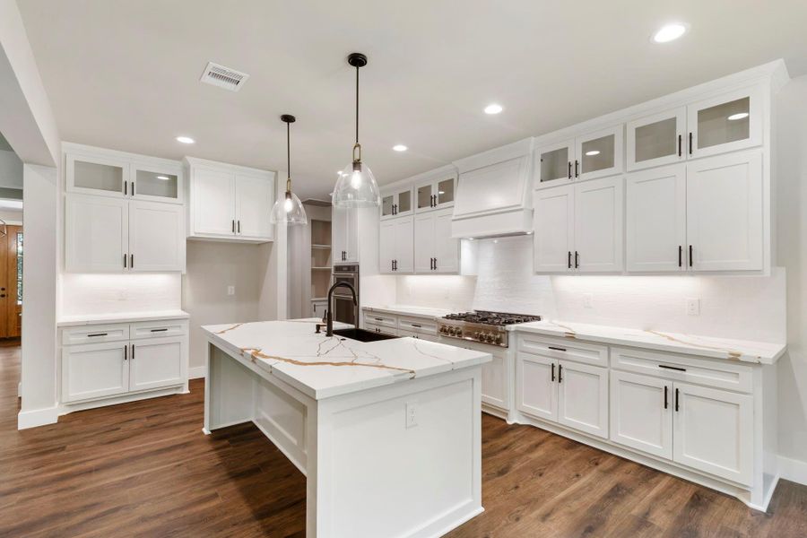 Discover modern elegance in this stylish kitchen featuring sleek cabinetry with gold hardware, a stunning quartz island, and sophisticated pendant lighting, creating the perfect blend of luxury and functionality.