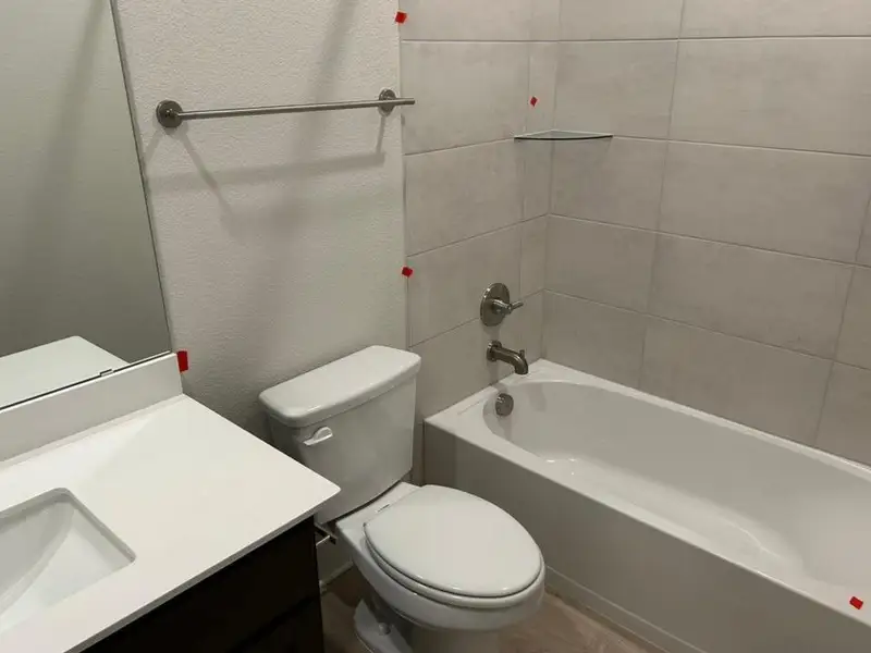 Bathroom featuring tub / shower combination, vanity, a textured wall, and wood finished floors