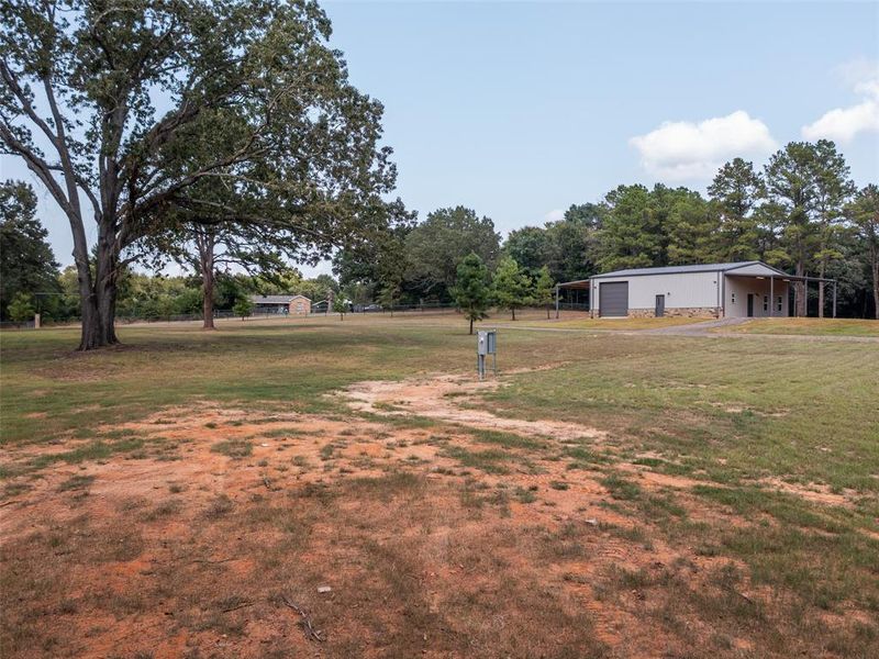 View of grassy yard with a pole building, an outdoor structure, and a garage