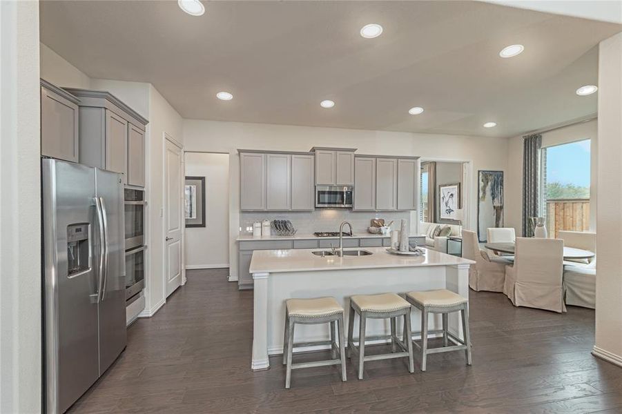 Kitchen featuring gray cabinets, stainless steel appliances, recessed lighting, decorative backsplash, and dark wood-style flooring