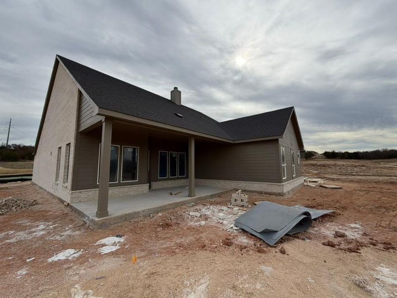 Back of house with a patio, brick siding, a chimney, and roof with shingles Back of house with a patio, brick siding, a chimney, and roof with shingles