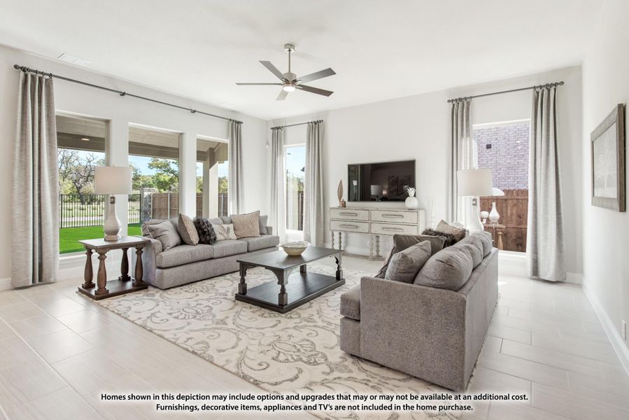 Bright living room with gray sofas, ceiling fan, and large windows overlooking a backyard patio. Bright living room with gray sofas, ceiling fan, and large windows overlooking a backyard patio.
