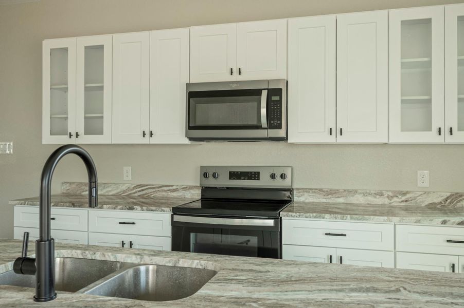 Kitchen with glass insert cabinets, stainless steel appliances, and white cabinets