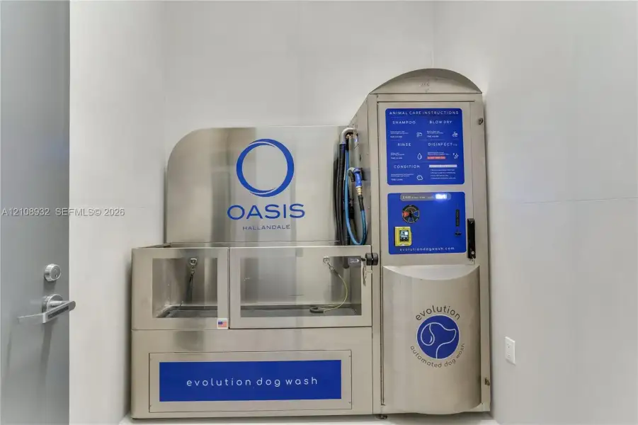 Stainless steel automated pet washing station featuring a built-in spray nozzle, integrated control panel, and large-format wall tiling