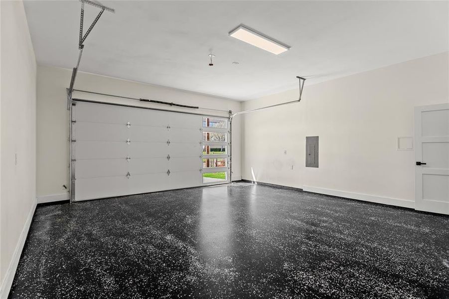 Garage with baseboards and electric panel