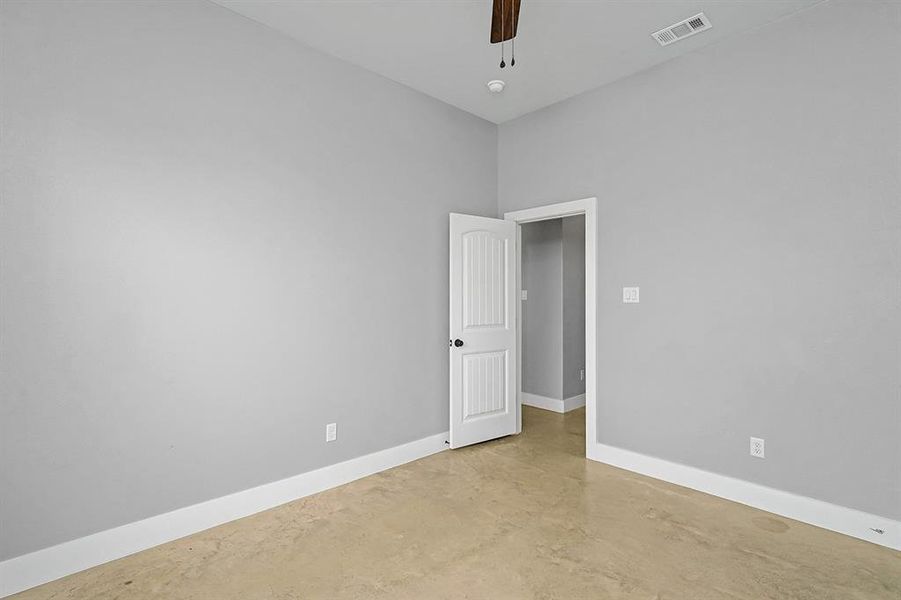 Unfurnished room with finished concrete floors, baseboards, and ceiling fan