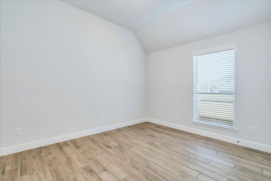 Unfurnished room with vaulted ceiling and light wood-style flooring