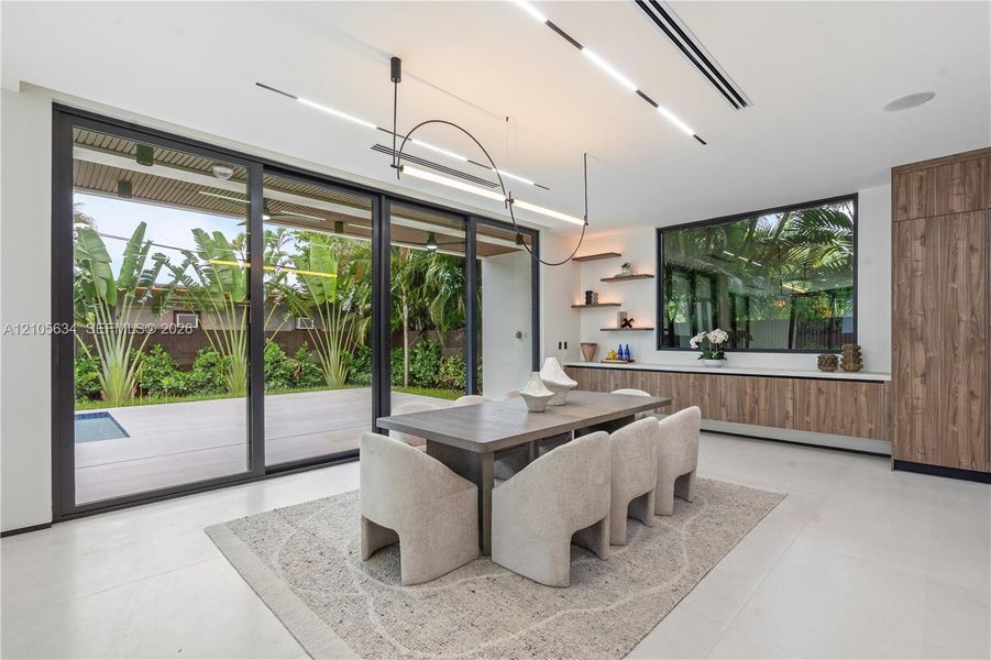 Large-scale sliding glass doors, contemporary linear LED lighting, custom wood-finish cabinetry, floating wall shelves, and expansive smooth-finish flooring
