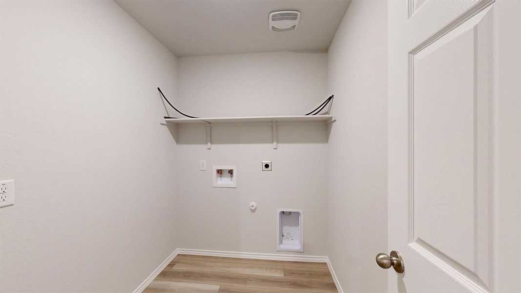 Dedicated laundry space featuring wood-finish flooring, white walls, and a built-in storage shelf