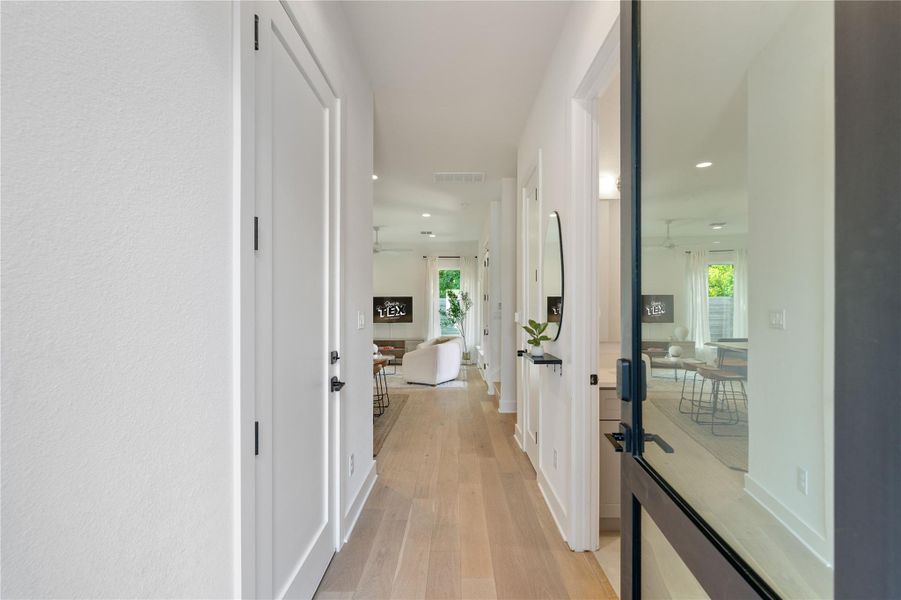 Smooth wood floors guide the eye from the threshold through a bright, minimalist entryway.