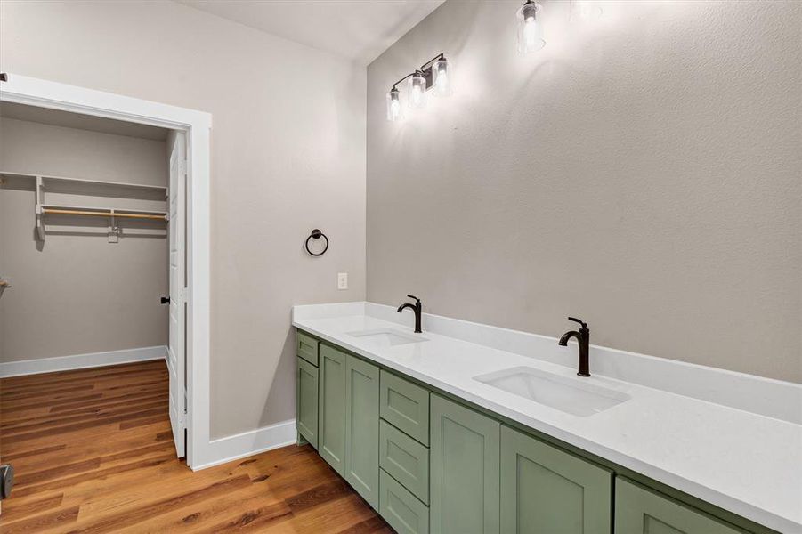 Full bathroom featuring double vanity, dark wood-type flooring, and a walk in closet