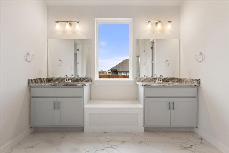 Bathroom featuring light marble finish flooring and two vanities
