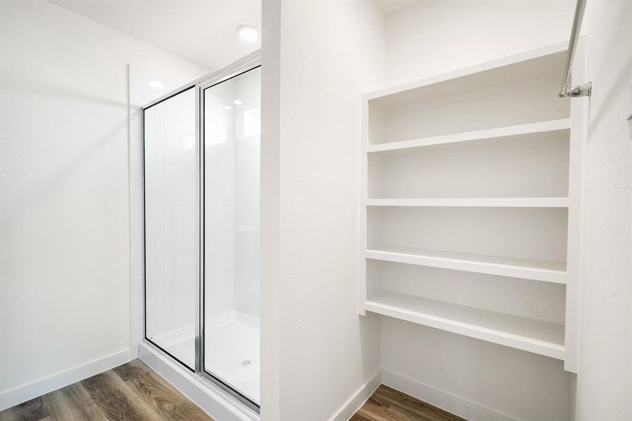 This additional view of the primary bath showcases the oversized walk-in shower with tile surround, perfect for soaking after a long day, and a convenient linen nook.