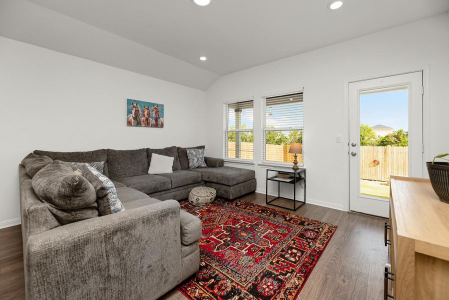 Living room with recessed lighting, lofted ceiling, and dark wood-style flooring