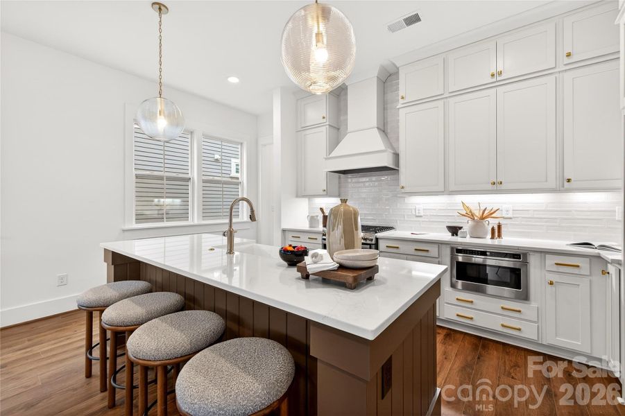 The open kitchen showcases stacked cabinetry, a gas range and microwave drawer, highlighted by beautiful quartz countertops. Perfect for entertaining!