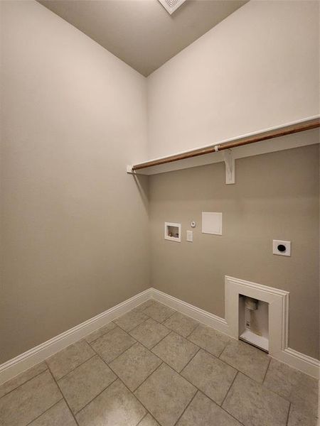 Clothes washing area featuring light tile patterned floors, electric dryer hookup, washer hookup, and hookup for a gas dryer