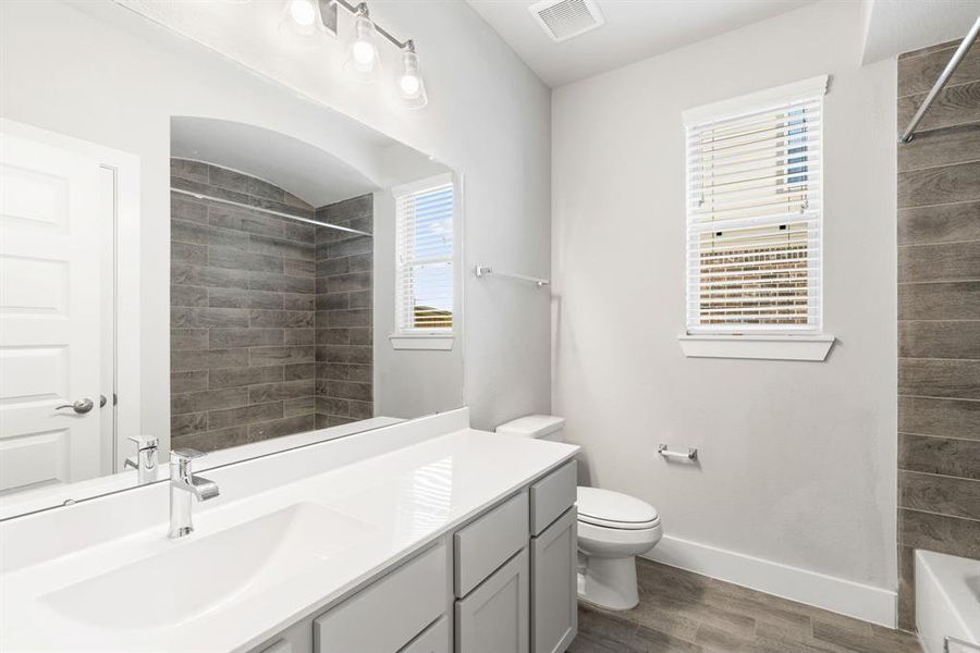 Experience sophistication in the secondary bathroom, where tile flooring complements a bath/shower combo with tile surround. Light wood cabinets complete with a beautiful light countertop, enhances the space for a truly inviting ambiance. Sample photo of completed home with similar floor plan. As-built interior colors and selections may vary.