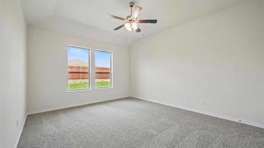 Carpeted empty room featuring vaulted ceiling and ceiling fan