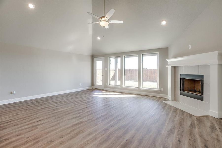 Unfurnished living room featuring high vaulted ceiling, a fireplace, light wood-type flooring, and ceiling fan Unfurnished living room featuring high vaulted ceiling, a fireplace, light wood-type flooring, and ceiling fan