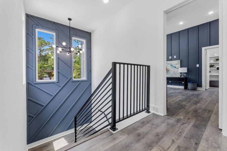 Modern interior staircase with contemporary railing and striking accent wall, bathed in natural light from tall windows.
