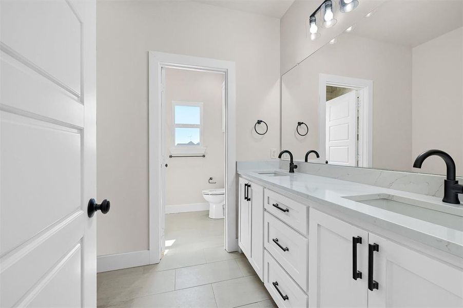 Bathroom featuring tile patterned flooring, vanity, and toilet