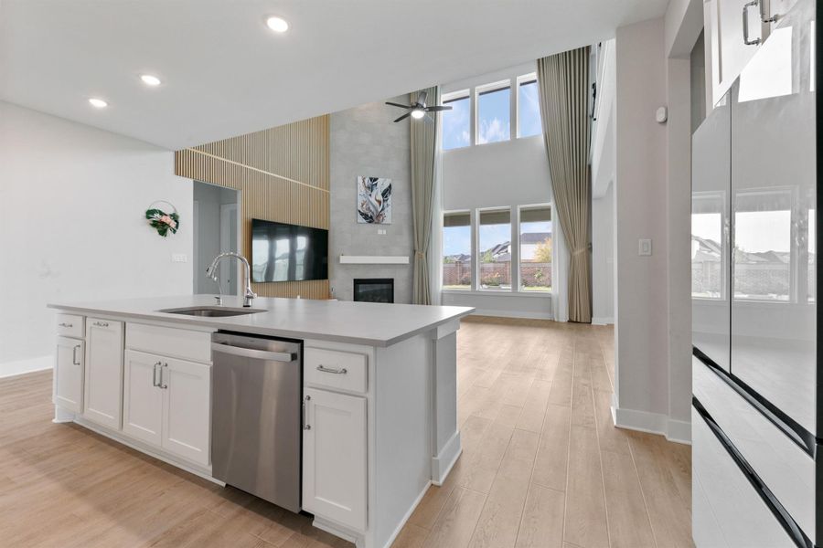 Bright and open kitchen overlooking the living area, featuring a large center island with bar seating, modern finishes, and expansive windows that fill the space with natural light. Perfectly designed for both entertaining and everyday living.