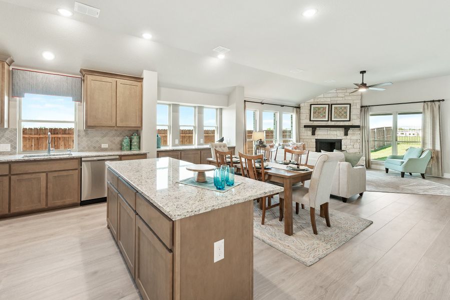 Open-concept kitchen with granite island flowing into dining area and living room with stone fireplace and hardwood floors Open-concept kitchen with granite island flowing into dining area and living room with stone fireplace and hardwood floors