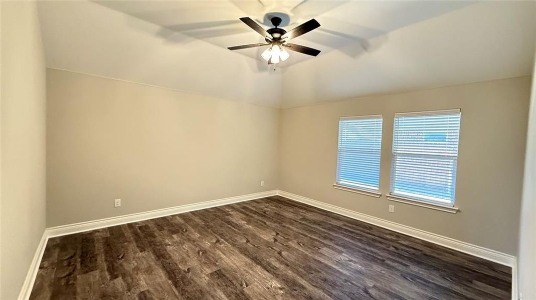 Empty room featuring lofted ceiling, dark wood-type flooring, and ceiling fan