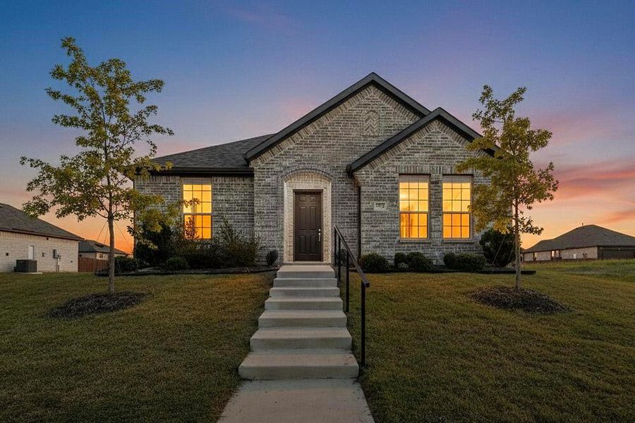 French country home featuring brick siding and a yard French country home featuring brick siding and a yard