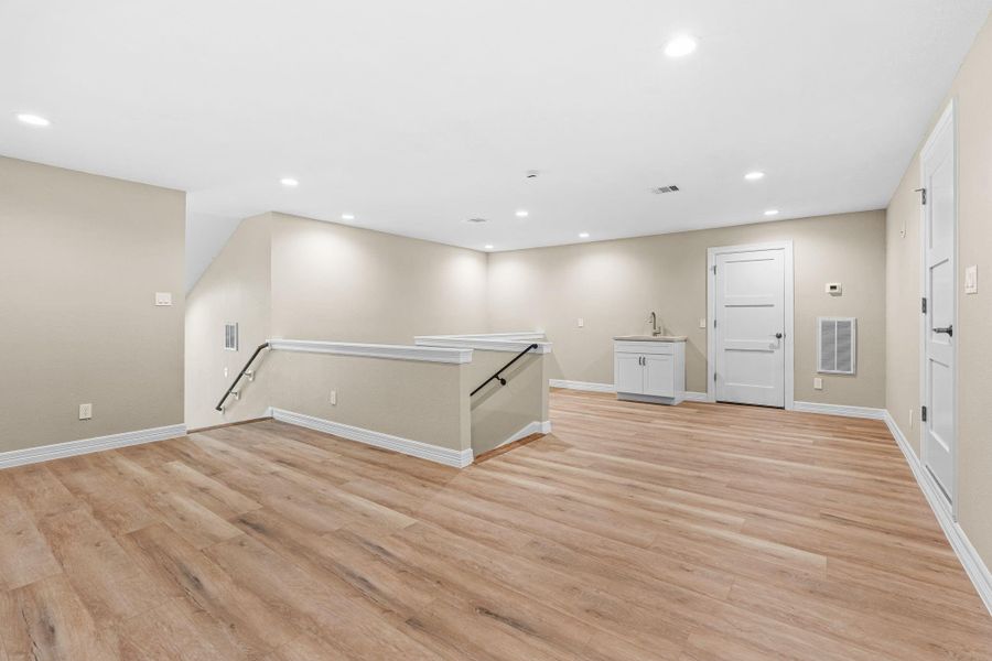 Spacious upstairs game room or flex area with recessed lighting and open floor plan.