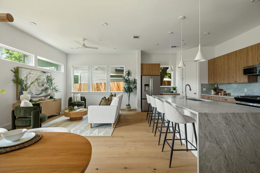 An open concept living and kitchen area with light hardwood floors and bright white walls. An open concept living and kitchen area with light hardwood floors and bright white walls.