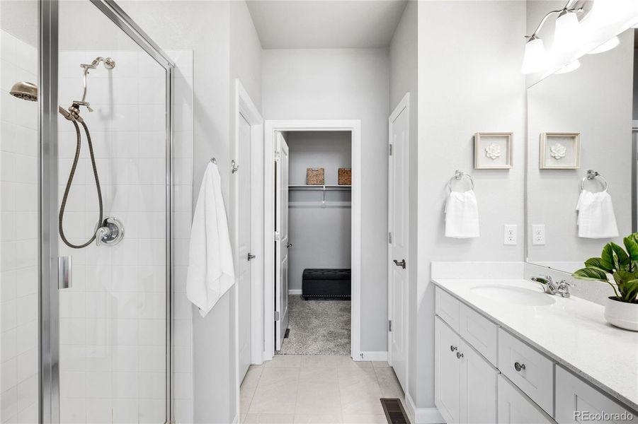 The neutral primary bathroom has a standing shower, linen closet, dual sinks and a water closet