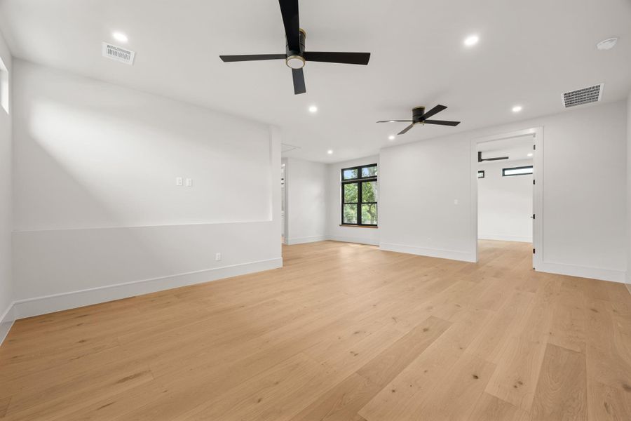 Rich hardwood flooring stretches across a light-filled living area featuring clean lines.