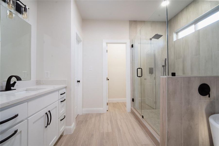 Bathroom with baseboards, a shower stall, vanity, and wood finished floors